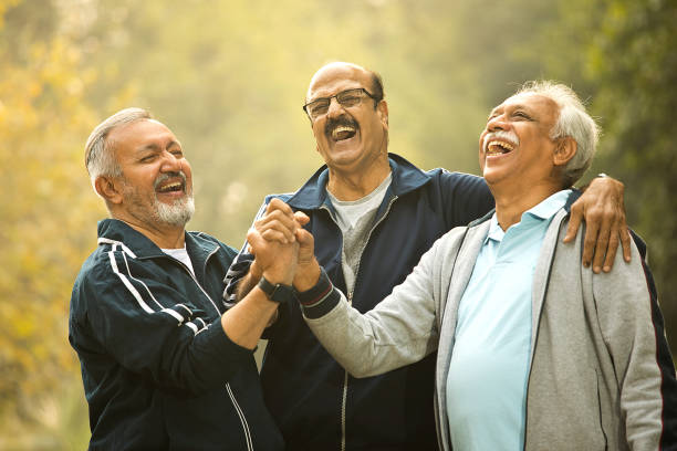 Cheerful old male friends stacking hands together at park